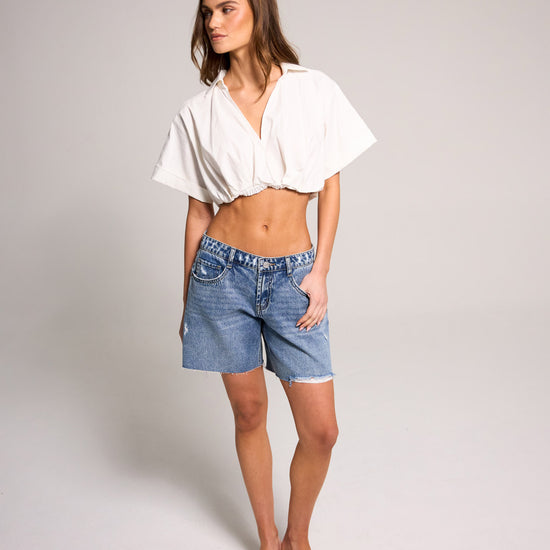 Stylish model showcasing Belle's Baggy Bermuda Short - Medium Indigo made of 100% cotton for a trendy look.